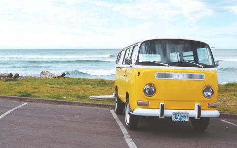 Yellow VW bus in parking lot near ocean